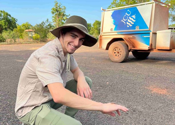 JCU Bachelor of Science student Tomas Cooney smiling with a small lizard on his hand. 