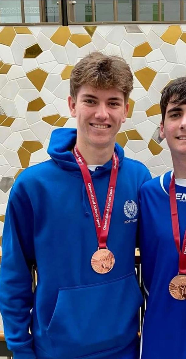 Benson in his North Queensland School Sport jumper with a medal around his neck. 